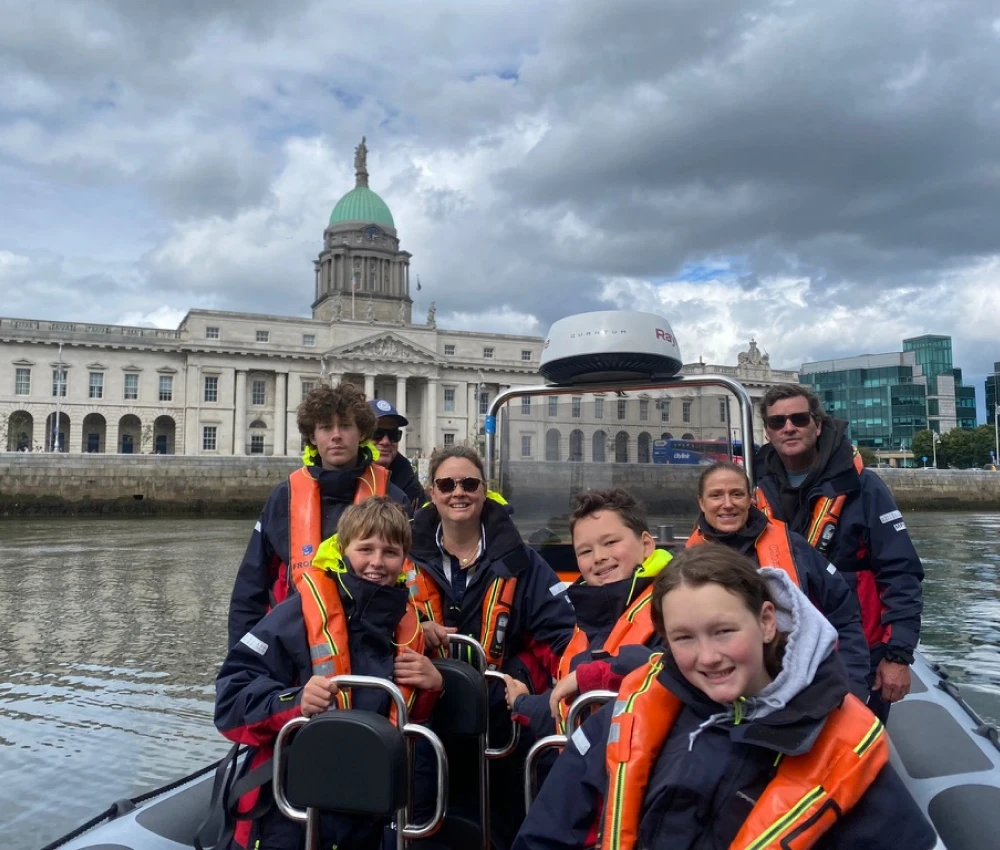 Group of people on a boat tour wearing life jackets in front of the Custom House in Dublin, Ireland