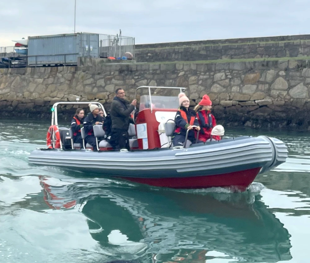 Students enjoying an educational boat tour on the River Liffey in Dublin, with a guide explaining historical landmarks.