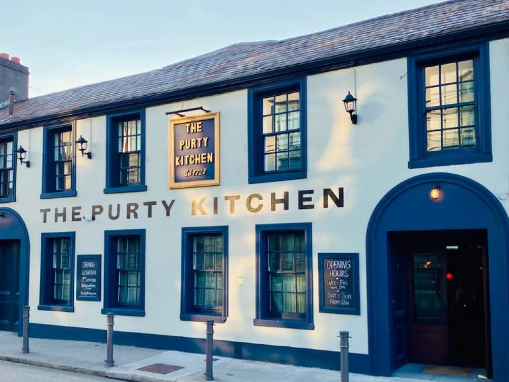 Exterior of The Purty Kitchen restaurant with blue-framed windows, chalkboard signs, and traditional white facade